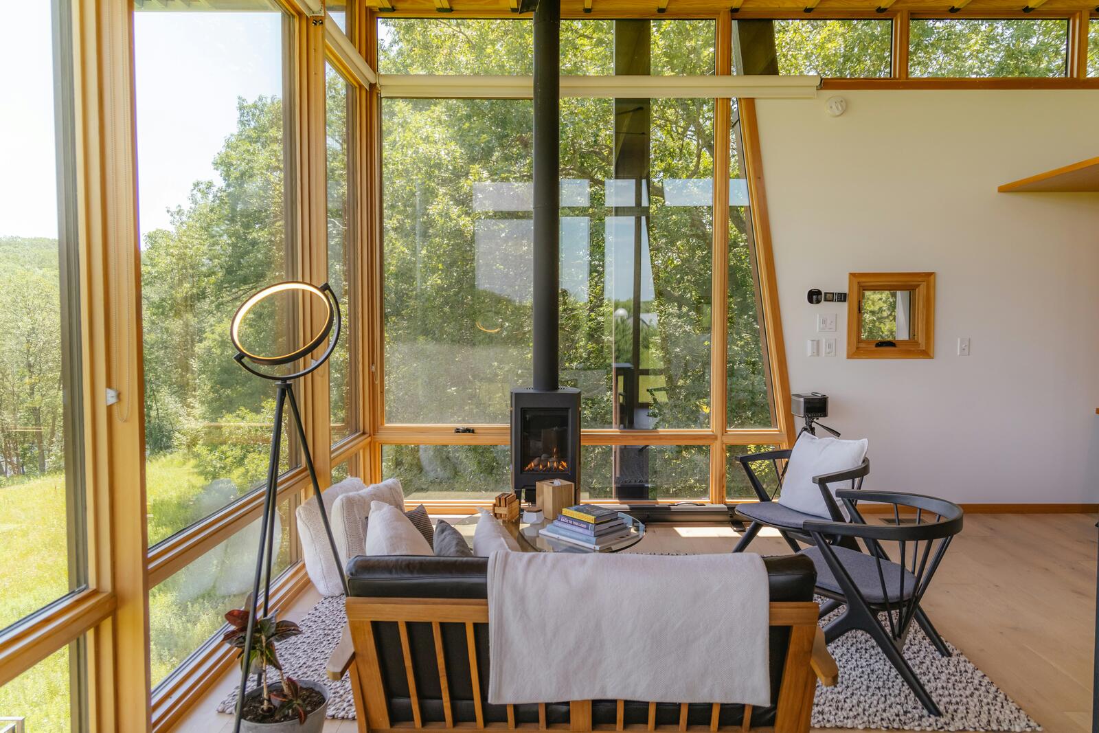 A sun-filled room with floor-to-ceiling windows looking onto the trees