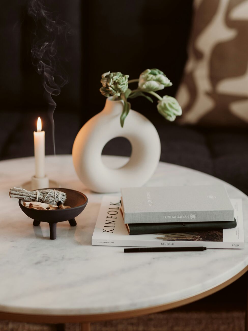 Styled tabletop with a ceramic vase, candle and books